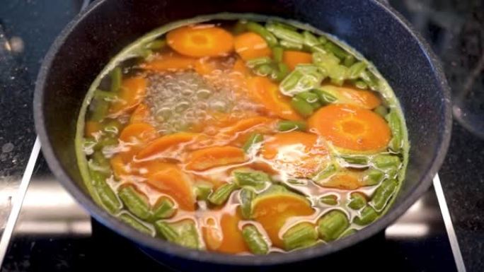 在带有大理石锅的电炉中煮沸西兰花和胡萝卜作为减肥食品的烹饪过程。