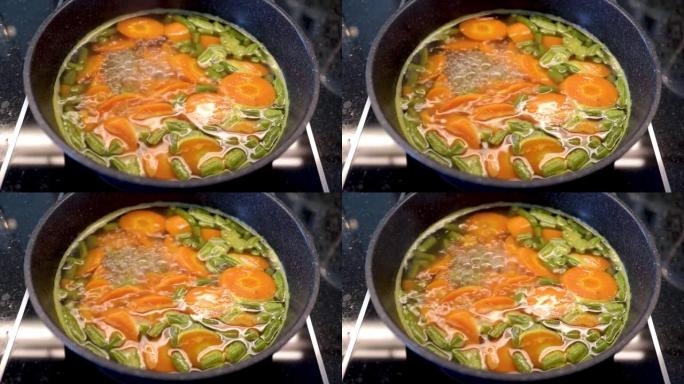 在带有大理石锅的电炉中煮沸西兰花和胡萝卜作为减肥食品的烹饪过程。