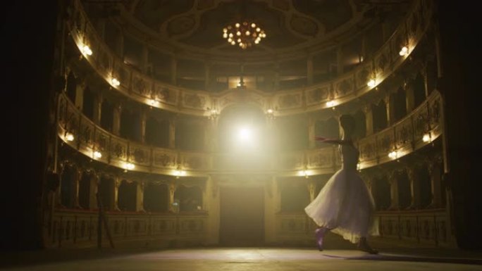 穿着脚尖鞋和白色短裙的芭蕾舞女演员的慢动作镜头在经典的剧院舞台上跳舞和排练，并带有戏剧性的灯光。优美