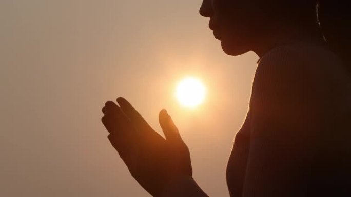 女人在美丽的日出背景上祈祷的剪影，视频4k慢动作。