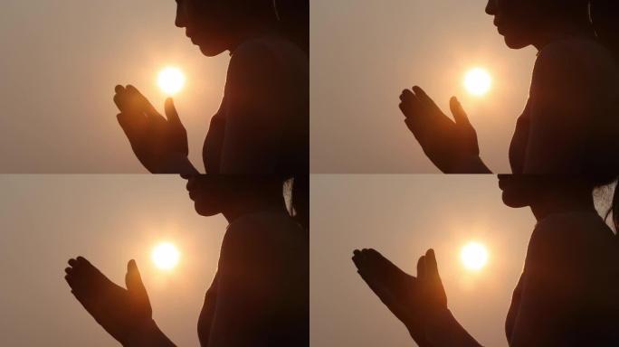 女人在美丽的日出背景上祈祷的剪影，视频4k慢动作。