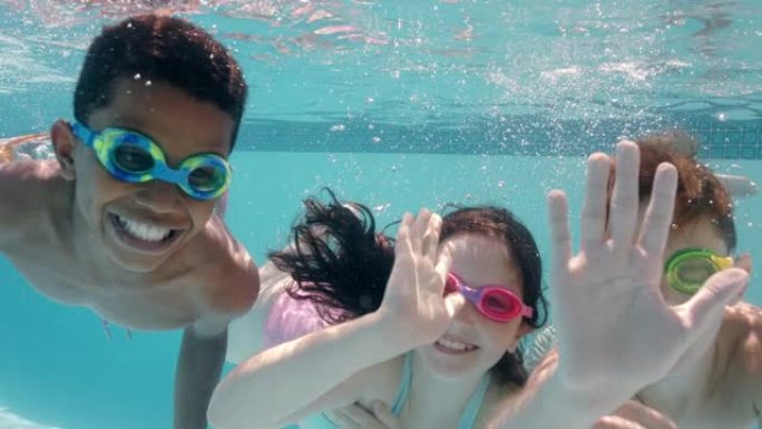 快乐的孩子在游泳池水下游泳微笑挥舞双手的孩子享受游泳在暑假一起漂浮在清澈的水中