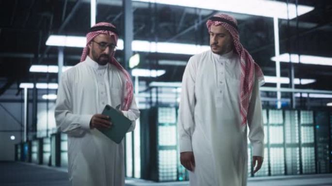 在现代数据中心: 中东工程师和IT专家在服务器机房工作，与平板电脑交谈，进行系统维护检查。做数据库诊