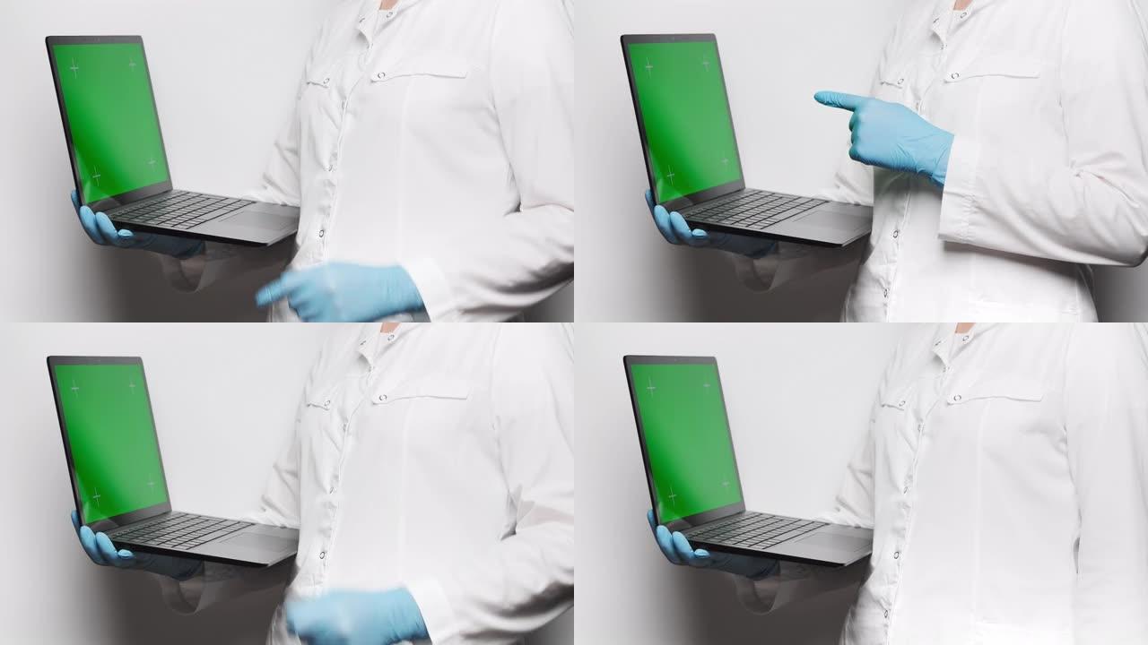 身穿白色外套和蓝色手套的医生拿着带有跟踪点的绿色屏幕笔记本电脑，将手指指向屏幕。4k，复制空间，慢动