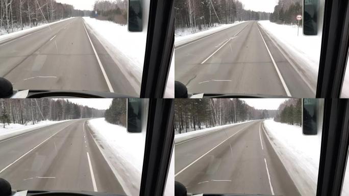 4k视频。开车时从汽车内部穿过挡风玻璃到道路，路边积雪和树木，空旷的冬季道路