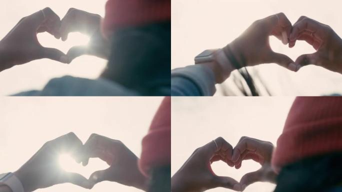 在爱情情人节概念中，近距离女性双手在日落时做心形手势