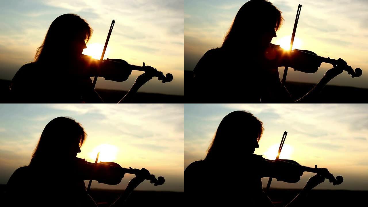 剪影女孩小提琴手在日落时拉小提琴。特写。