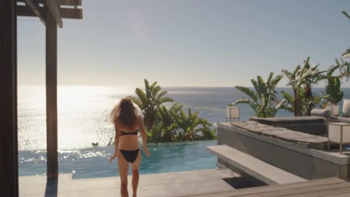 快乐的女人在豪华酒店的游泳池里跳，享受在热带度假胜地游泳，海景，在温暖的阳光明媚的日子里享受有趣的暑