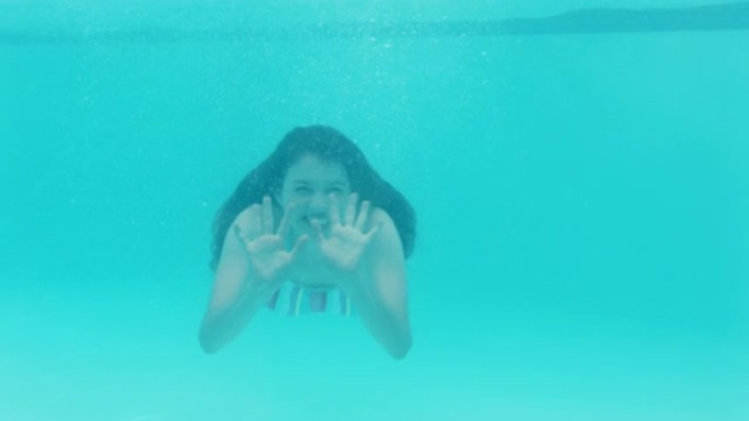 美丽的女人在游泳池水下游泳微笑挥手漂浮在蓝色水晶清澈的水中玩得开心在夏季4k