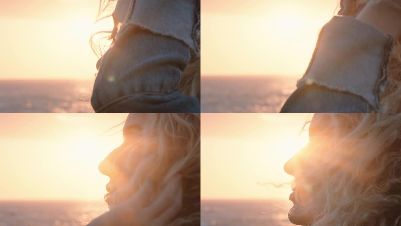 美丽的金发女子在日落时享受宁静的海边，沉思探索灵性的旅程，感受风吹头发的自由