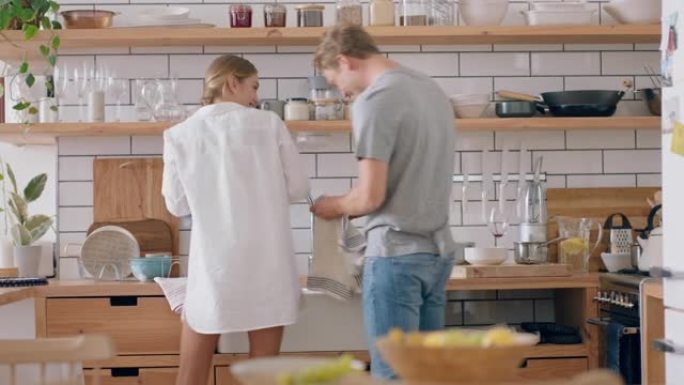 快乐的年轻夫妇洗碗在厨房玩得开心扔肥皂泡享受浪漫关系嬉戏做家务4k镜头