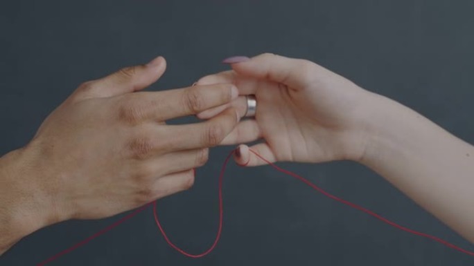 两只手绑着红色的弦触摸手指表达爱情享受灰色背景上的浪漫感觉