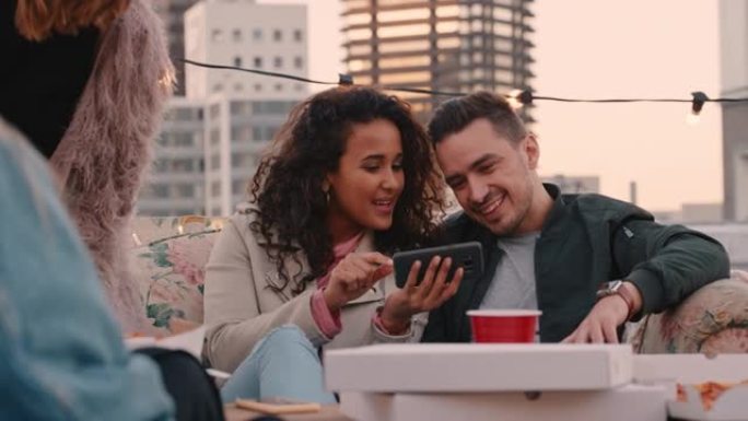快乐的多民族朋友享受周末屋顶派对喝酒使用社交媒体上的智能手机分享自拍照片
