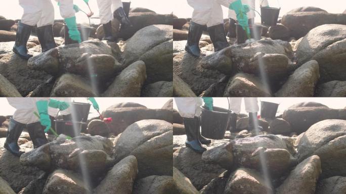 污染控制小组用刷子清洁海滩岩石上的油污