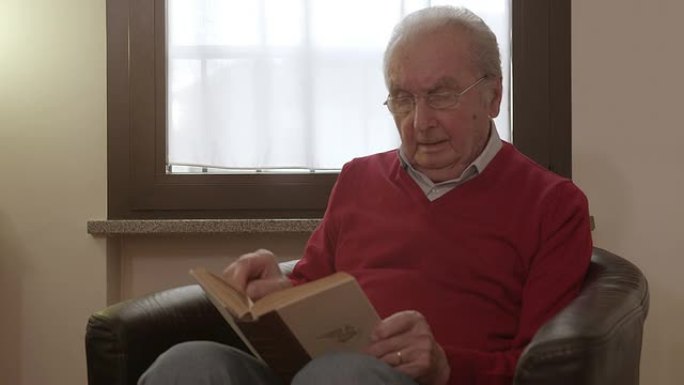 老人坐在扶手椅上看书
