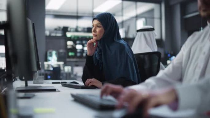 一位体贴的中东女性在一家科技公司办公室的电脑上工作的肖像。年轻女子为创新的互联网和软件服务项目编写软