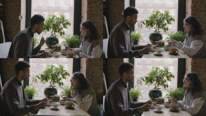 男人和女人在舒适的咖啡馆吃甜点和聊天享受早餐的侧视图