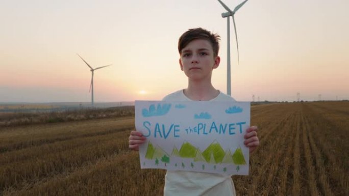 拯救星球海报抗议男孩在风力涡轮机上抱着他的面前，看着相机慢动作。儿童保护自然。童年。生态。替代能源。