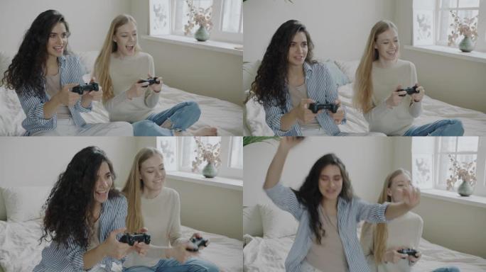 快乐的年轻女性朋友玩电子游戏笑着享受比赛坐在家里的床上