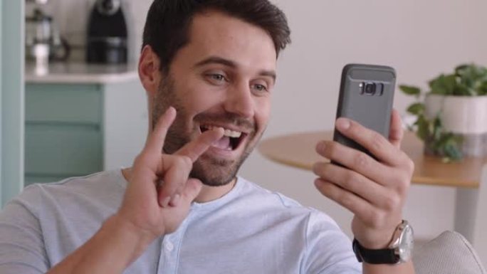 年轻的聋哑男子手持智能手机进行视频聊天，使用手语挥舞着享受手机上的连接聊天
