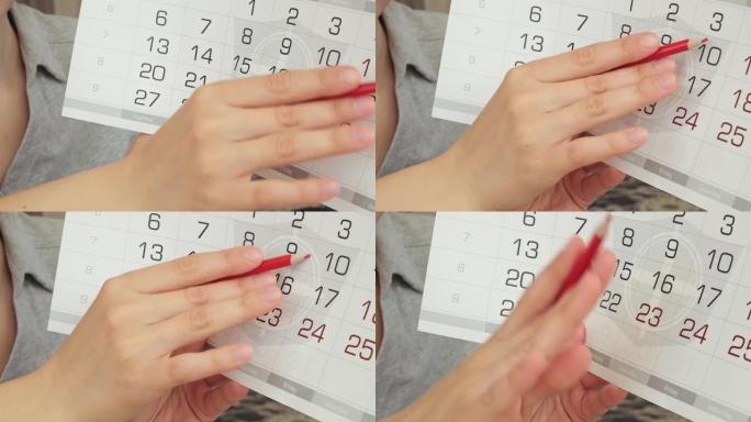 三月月字是用日历写的。一只女性手在日历上盘旋日期。红色铅笔。具有动态变焦的高质量FHD镜头。特写。