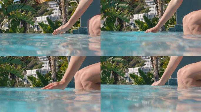 阳光明媚的4k，女人用手轻轻嬉戏地触摸游泳池水