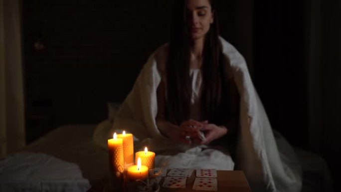 一个女人在黑暗中通过燃烧的蜡烛的光阅读卡片。
