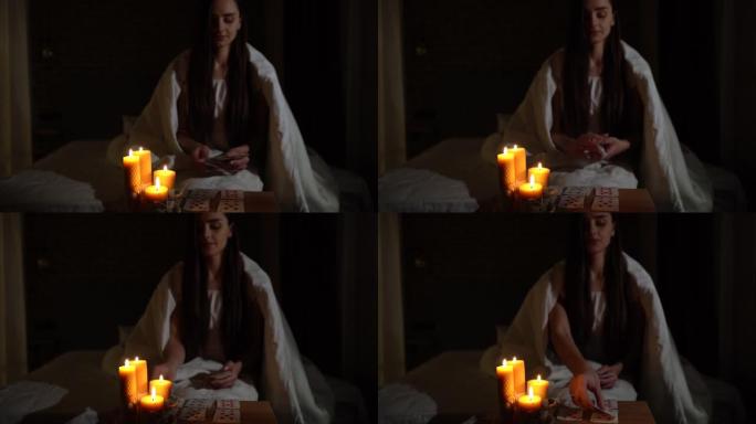 一个女人在黑暗中通过燃烧的蜡烛的光阅读卡片。