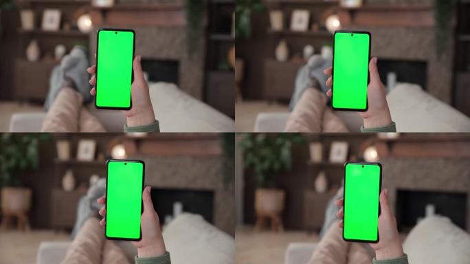 女人躺在沙发上的观点使用色度键绿色屏幕的智能手机。用于广告应用程序或流媒体服务的Chromakey模