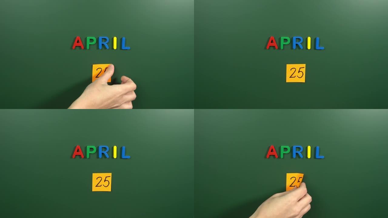 4月25日日历日用手在学校董事会上贴一张贴纸。25 4月日期。4月第二十五天。第25个日期编号。25