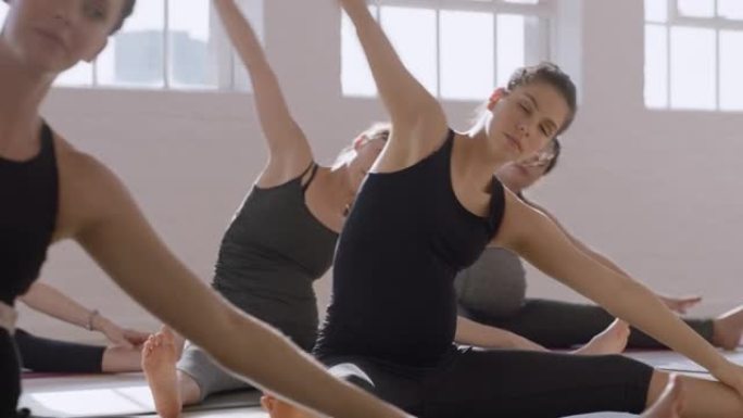 年轻的怀孕白人妇女在瑜伽课上练习伸展运动享受团体健身锻炼日出健康生活方式承诺