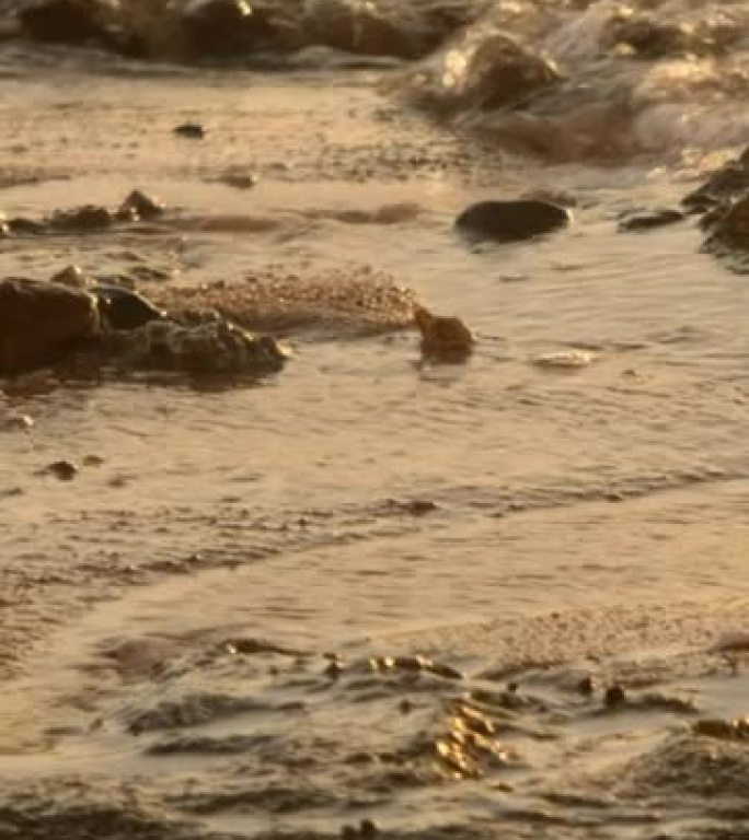 垂直视频，慢动作，自然背景，波浪冲向砂岩海岸。海浪正慢慢飘入沙滩。特写