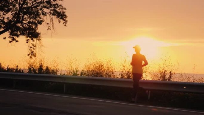 日落时沿着海边的道路奔跑的女人的剪影。活跃的中年人