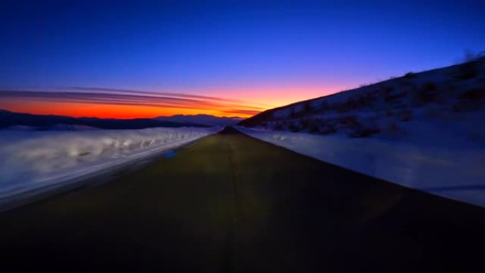 黄昏时在雪山路上行驶。