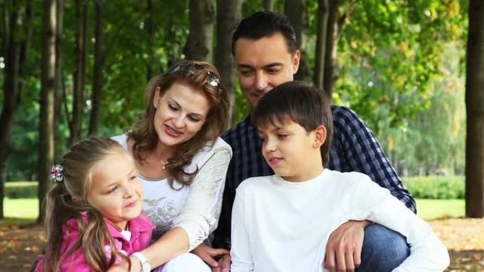 有男孩和女孩的家庭坐在公园里