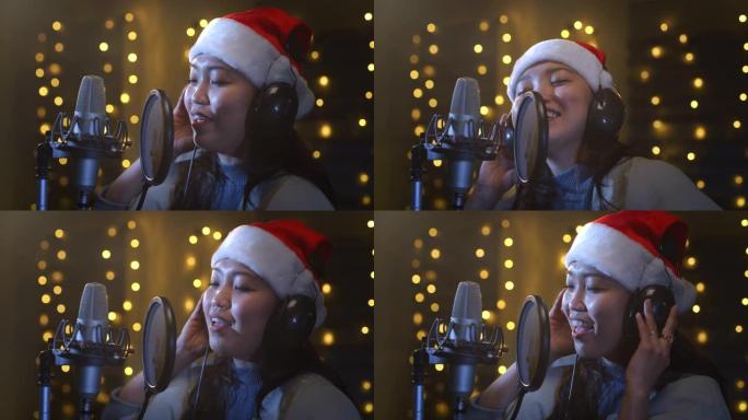 专业亚洲女歌手的特写肖像在录音室为她的圣诞节专辑录制了一首歌。热情洋溢的年轻艺术家，戴着圣诞老人的帽
