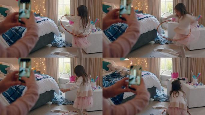 快乐的小女孩在五颜六色的卧室里玩呼啦圈，母亲用智能手机在社交媒体上分享照片