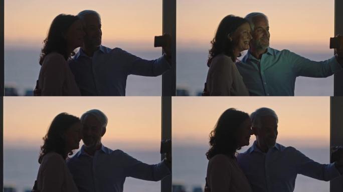 幸福的老夫妻在日落时使用智能手机拥抱在社交媒体上享受成功的退休分享假期
