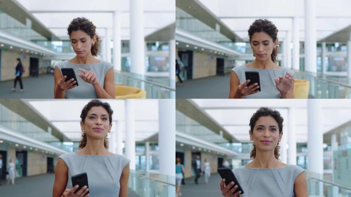 西班牙裔女商人用智能手机发短信走在公司办公室用手机打短信检查电子邮件工作中成功的女高管4k镜头