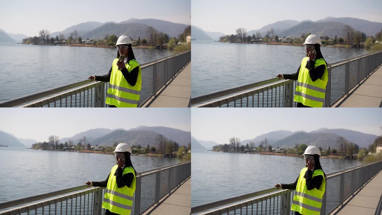 女工程师站在背心，防护眼镜和安全帽头盔上，看着位置