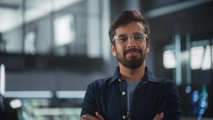 英俊的印度人戴着眼镜，穿着深蓝色衬衫，微笑着看着相机。在技术研究机构担任工程师或科学家的南亚年轻人