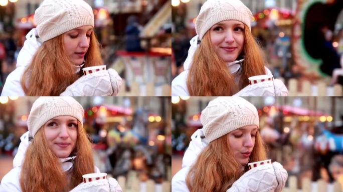 年轻迷人的女人在圣诞集市上喝热茶。