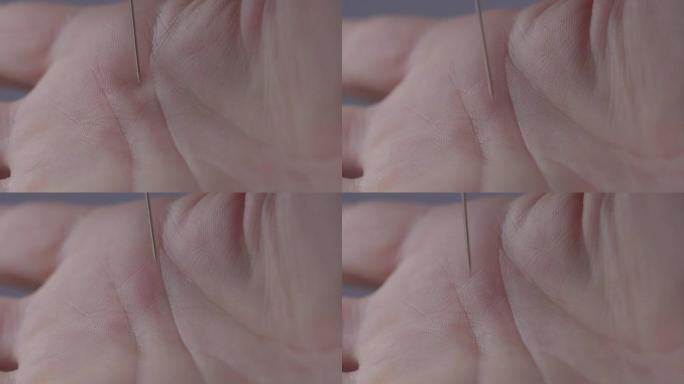 针的宏观特写刺破了一个人的手掌。危险地将手皮肤与锋利的缝纫针接触。4K