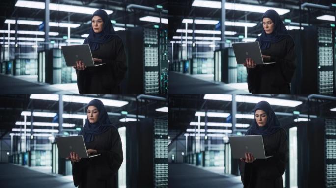穆斯林女性数据中心IT工程师站在一个装有服务器机架的房间里。云计算架构师使用笔记本电脑为网络安全和数