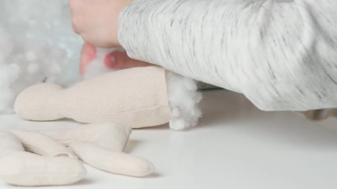 视频制作毛绒玩具，创造爪子和身体，在桌子上填充棉花。裁剪女性手缝纫玩具