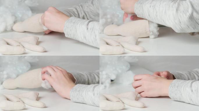 视频制作毛绒玩具，创造爪子和身体，在桌子上填充棉花。裁剪女性手缝纫玩具