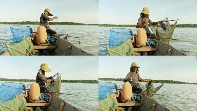 独木舟中的虾渔民从河中拉出水网，捕获虾，诱饵网并将其推入河中