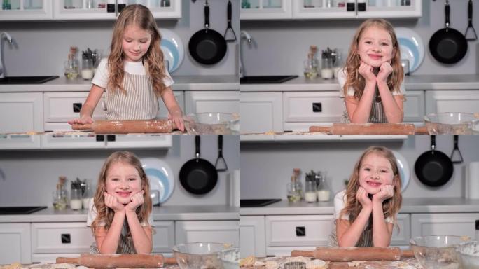 用rolling面杖的可爱的小女孩的肖像准备小麦粉面包，微笑着看着相机，然后藏在厨房的桌子下面