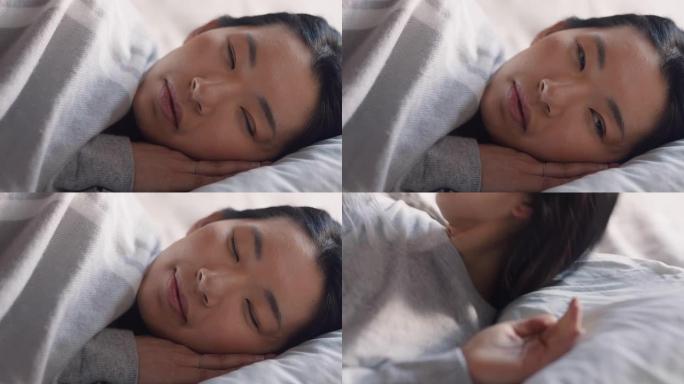 美丽的亚洲女人睡个好觉后在床上醒来，微笑着为新的一天做好准备