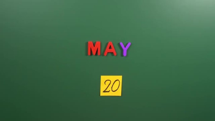 5月20日日历日用手在学校董事会上贴一张贴纸。5月20日。5月20日。第20个日期号。20天日历。二